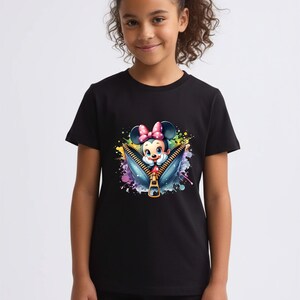 May include: Black t-shirt featuring a colorful graphic of Minnie Mouse emerging from a zipper. The design includes a pink bow, blue eyes, and a vibrant splash of watercolor-style paint. The shirt is worn by a young person.