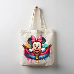 May include: A cream-colored tote bag featuring a colorful illustration of Minnie Mouse. Minnie Mouse is peeking out of a red and blue zipper, with a pink bow and white polka dots. The bag has a simple design with a handle.
