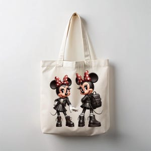 Peut inclure: Sac fourre-tout cr&egrave;me avec un motif de deux souris de dessin anim&eacute; portant des vestes, des jupes et des bottes noires. Chaque souris a un n&oelig;ud rouge &agrave; pois blancs. Une souris porte un sac &agrave; dos. Le sac a un design simple et neutre.