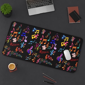 May include: A black rectangular mouse pad covered in colorful musical notes, treble clefs, and musical symbols. The notes are in shades of pink, yellow, blue, green, and purple. A white computer mouse sits on the right side of the pad.