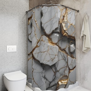 Puede incluir: Una cortina de ducha gris con un diseño de mármol y vetas doradas. La cortina está en un baño con un inodoro blanco y una toalla. El diseño le da al baño un aspecto moderno.