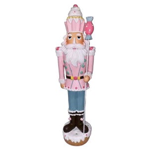 May include: A pink and white Christmas nutcracker figurine with a candy cane in its hand. The nutcracker is wearing a pink and white hat with a white frosting design. The nutcracker is standing on a white base with a brown base.