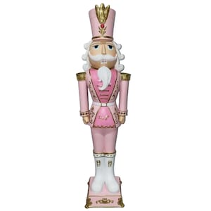 May include: A pink and gold Christmas nutcracker figurine with a white beard and a red jewel on its hat.