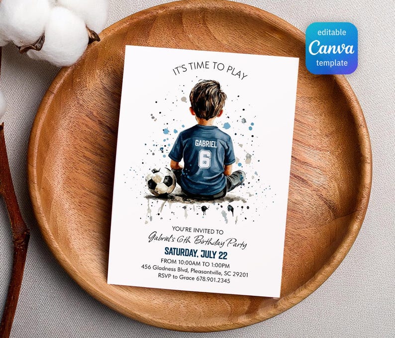 May include: A white invitation card with the text "IT'S TIME TO PLAY" and "Gabriel's 6th Birthday Party". The card features a watercolor illustration of a boy in a soccer jersey with a soccer ball. The card is on a wooden plate.