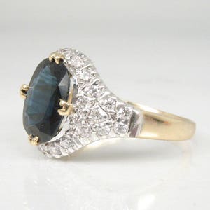 May include: A gold ring with a large oval blue gemstone surrounded by smaller white gemstones.