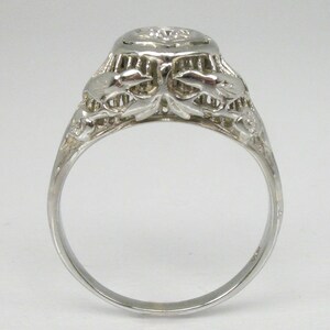 May include: A silver filigree engagement ring with a round, clear diamond center stone.