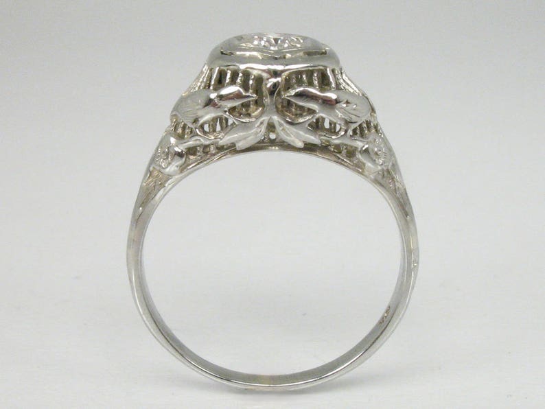 May include: A silver filigree engagement ring with a round, clear diamond center stone.