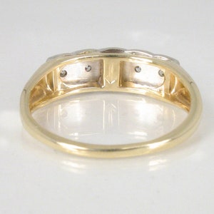 Puede incluir: Un anillo de banda de oro con tres peque&ntilde;os diamantes engastados en la banda. El anillo est&aacute; hecho de oro de dos tonos, con una banda de oro amarillo y detalles de oro blanco.