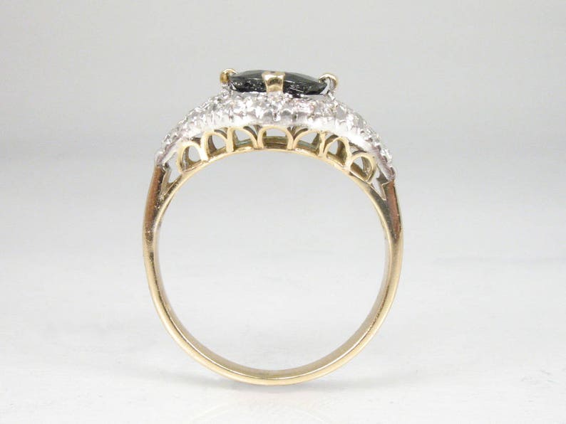 May include: A gold ring with a black gemstone surrounded by smaller white gemstones.
