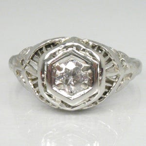 May include: A silver filigree ring with a single round diamond in the center.