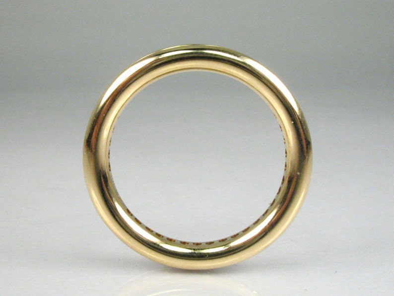 May include: A gold band ring with a smooth, polished finish. The ring is set with a row of small, round stones.