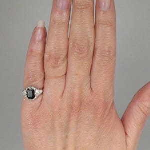 May include: A silver ring with a black oval gemstone surrounded by smaller white gemstones.