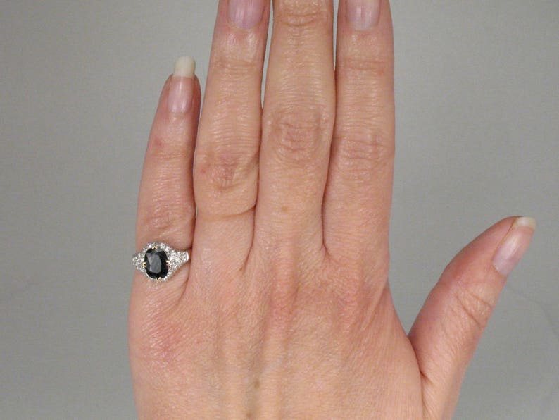 May include: A silver ring with a black oval gemstone surrounded by smaller white gemstones.