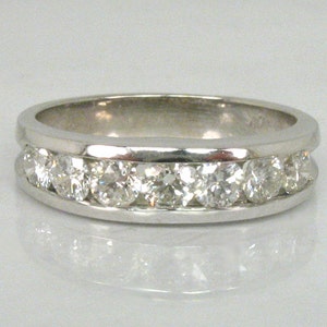May include: A silver band ring with a row of clear round diamonds set in a channel setting.