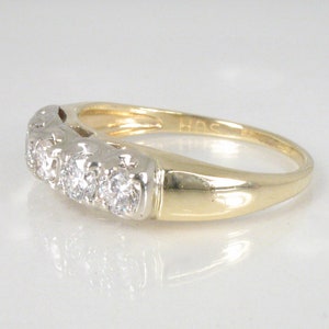 Puede incluir: Un anillo de banda de oro con una fila de peque&ntilde;os diamantes engastados en metal blanco. El anillo est&aacute; marcado con "14K" en el interior.