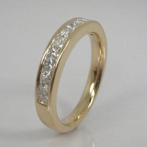 May include: A gold band ring with a row of small, clear diamonds set in a channel setting.