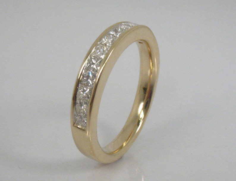 May include: A gold band ring with a row of small, clear diamonds set in a channel setting.