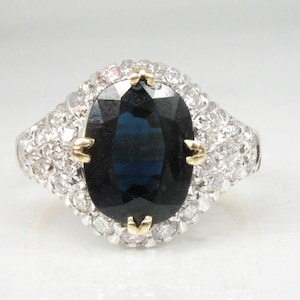 May include: A silver ring with a large oval-shaped blue sapphire surrounded by smaller diamonds.
