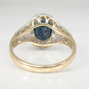 May include: A gold ring with a blue oval gemstone surrounded by a halo of smaller white gemstones.