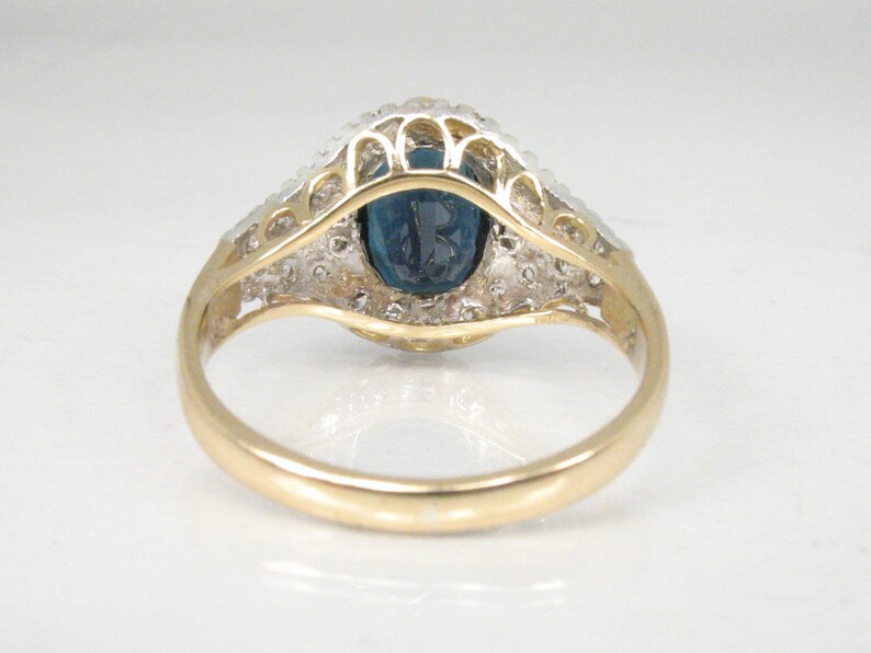May include: A gold ring with a blue oval gemstone surrounded by a halo of smaller white gemstones.