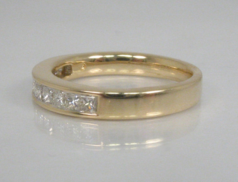 May include: A gold band with a row of small square-shaped diamonds.