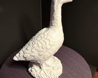 May include: A detailed, off-white goose figurine. The sculpture has a long neck and textured feathers, standing on a textured base. The goose is a decorative item, likely for home decor.