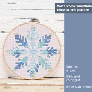 May include: A cross stitch pattern of a watercolor snowflake in shades of blue and yellow on a white background. The pattern is 91 stitches wide by 89 stitches tall. The image includes the text "Watercolor snowflake cross stitch pattern", "Stitches: 91x89", "B&W grid", "color grid", and "list of DMC colors".