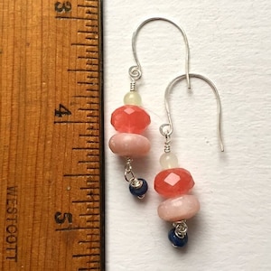 May include: A pair of silver dangle earrings with pink, red, and white gemstone beads and blue gemstone accents.