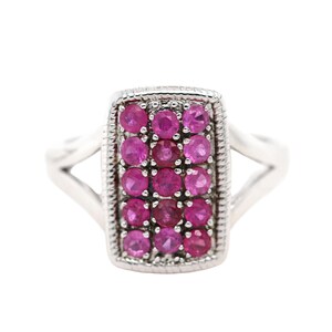 May include: A silver ring with a rectangular setting featuring a cluster of pink gemstones.