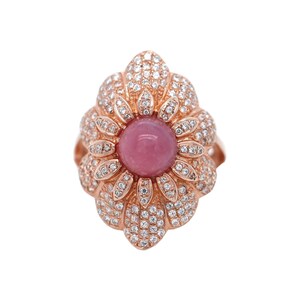 Könnte beinhalten: Ein Ring aus Roségold mit einem rosafarbenen Edelstein, der von klaren Zirkonia-Steinen umgeben ist. Der Ring ist in Form einer Blume gestaltet.