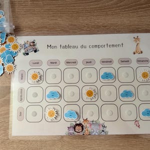 Peut inclure: Un tableau de comportement avec le texte "Mon tableau du comportement" et les jours de la semaine. Comprend des jetons en forme de soleil et de nuage. Le tableau a un thème animalier de dessin animé, avec une girafe et d'autres animaux.