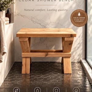 May include: A rectangular cedar shower bench with a light brown wood grain finish. The bench features a flat top surface supported by four sturdy legs arranged in an X-frame design with a horizontal support bar connecting the legs.