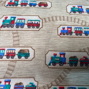 Może przedstawiać: Beżowy materiał z powtarzającym się wzorem zabawek lokomotyw i wagonów kolejowych. Pociągi są niebieskie, zielone, czerwone i brązowe. Pociągi znajdują się na brązowym torze z drewnianymi podkładami.