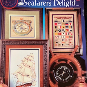 Może przedstawiać: Wzór do haftu krzyżykowego na projekt o tematyce morskiej o nazwie "Seafarers Delight". Wzór zawiera statek, kompas i tabelę flag morskich. Wzór pochodzi od Cross My Heart.