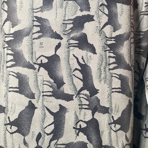 Może przedstawiać: Zbliżenie na tkaninę z powtarzającym się wzorem czarnych sylwetki ptaków na jasnoszarym tle.