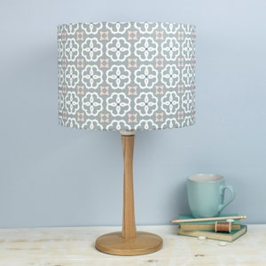 May include: A gray table lamp with a white and pink patterned lampshade. The lamp has a wooden base.
