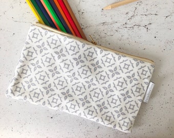 May include: A white pencil case with a gray geometric pattern and a gold zipper. The case is filled with colored pencils. The text "grace and favour home" is printed on the case.