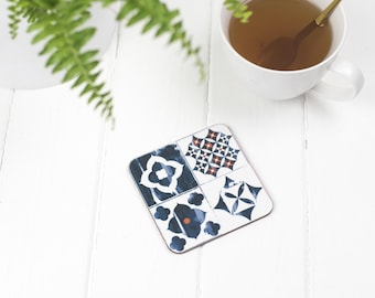 May include: A square blue and white patterned coaster with a red accent. The coaster is made of cork and has a smooth surface.