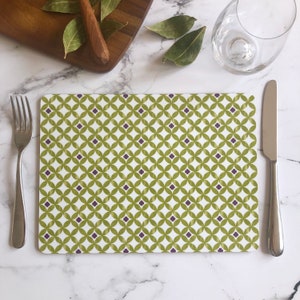 Pode incluir: Um tapete de mesa verde e branco com um padrão geométrico. O padrão apresenta pequenos círculos e quadrados em um design repetitivo. O tapete de mesa é feito de um material durável e é perfeito para uso diário.