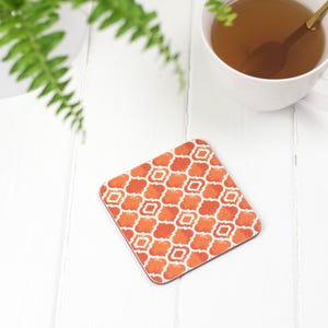 May include: Orange and white patterned coaster with a geometric design. The coaster is made of a durable material and is perfect for protecting surfaces from heat and spills.