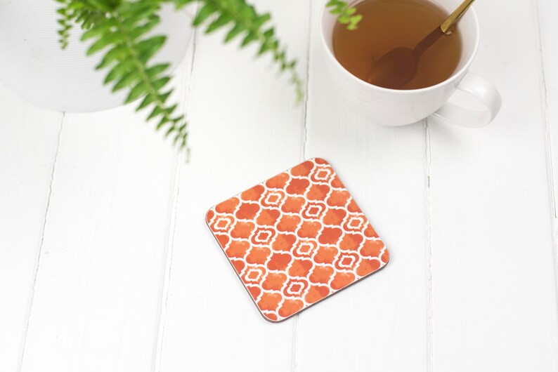 May include: Orange and white patterned coaster with a geometric design. The coaster is made of a durable material and is perfect for protecting surfaces from heat and spills.