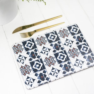 May include: A blue and white patterned placemat with a geometric design. The placemat is made of cork and has a smooth surface. It's a great way to add a touch of style to your dining table.