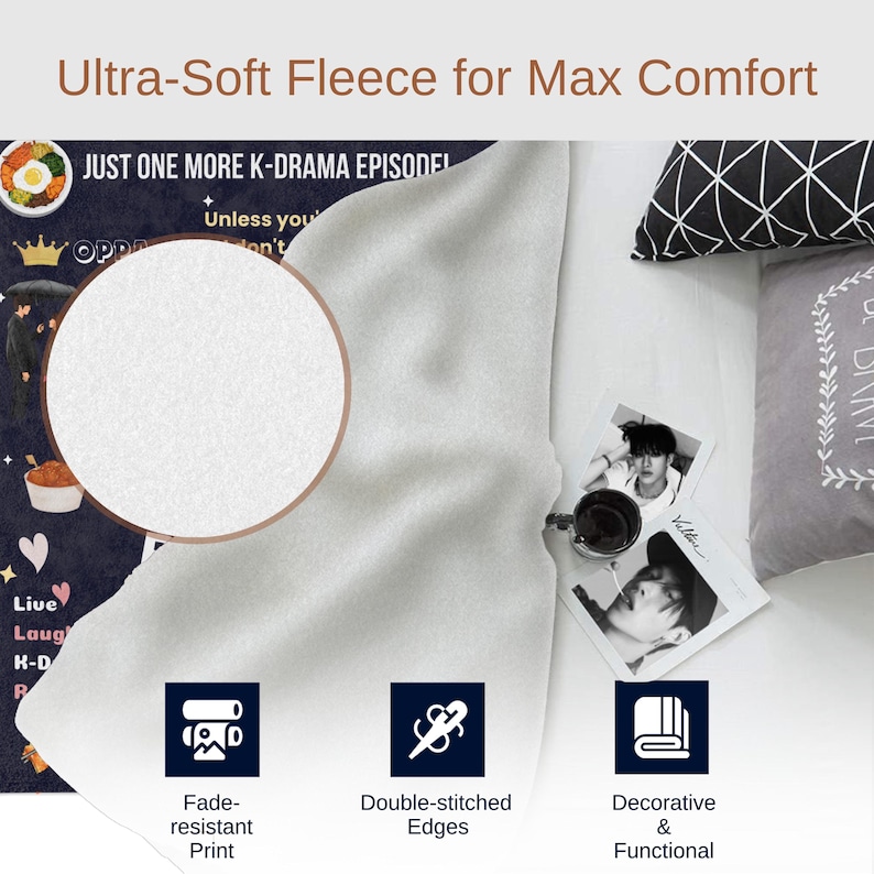 May include: A white fleece blanket with a black and white print featuring the text "Just one more K-drama episode!" and a heart with the text "Live Laugh K-Drama Repeat". The blanket is folded in half and has a white background with a black border. The blanket is shown on a white surface with a black and white patterned pillow and a gray pillow with a floral design. The blanket has double-stitched edges and a fade-resistant print.