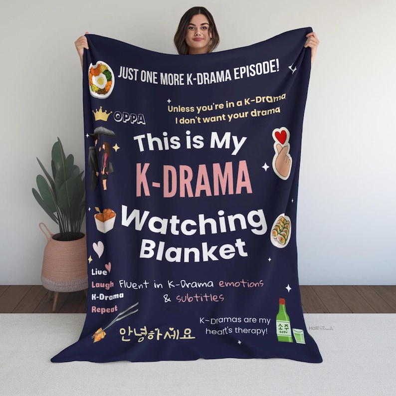 Woman holding a navy blue K-Drama Watching Blanket with playful text, icons like soju, kimbap, and hand hearts. Perfect for K-drama fans!