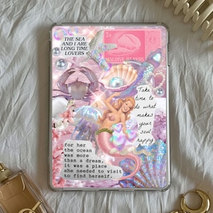 May include: A clear phone case with a collage design featuring a mermaid, seashells, and text. The design includes the phrases "THE SEA AND I ARE LONG TIME LOVERS" and "Take time to do what makes your soul happy."