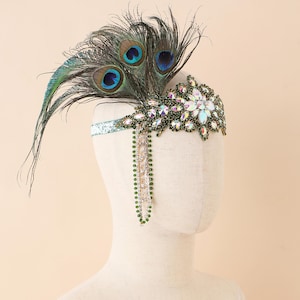 May include: A decorative headpiece with peacock feathers and sparkling embellishments. The headpiece has a floral design with iridescent crystals and a beaded fringe. The headband is a light blue colour with glitter.