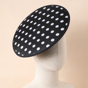 Puede incluir: Un sombrero negro y blanco de lunares con un ala ancha. El sombrero está hecho de un material suave y de tela.