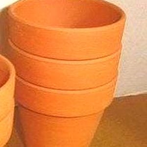 May include: A stack of four terracotta flower pots, each with a cylindrical shape and a slightly flared rim. The pots are a warm orange-brown color, and the texture appears to be slightly rough. The pots are stacked on top of each other.