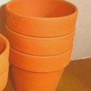 May include: A stack of four terracotta flower pots, each with a rounded rim and a slightly tapered shape. The pots are a warm, earthy orange color, and the texture appears to be slightly rough. The pots are stacked on top of each other.