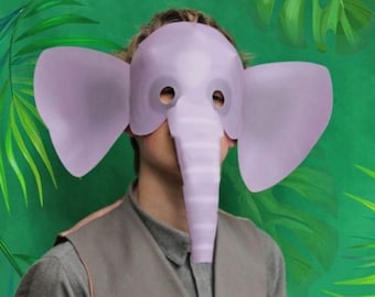 May include: A light purple elephant mask with large ears and a trunk. The mask is worn over the face. The person is wearing a gray vest and shirt. The background is green with tropical leaves.